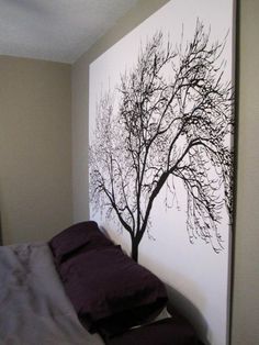 a bedroom with a tree painted on the wall next to a bed in front of it