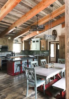 a kitchen and dining area with wooden beams on the ceiling, wood flooring and white chairs