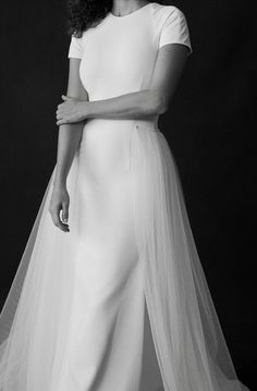 a woman in a white dress with a veil on her head is posing for a black and white photo