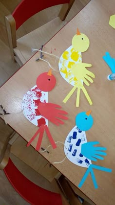 children's handprinted paper birds on a wooden table