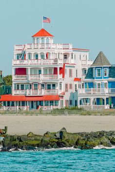 a large white building sitting on top of a sandy beach next to the ocean in front of it