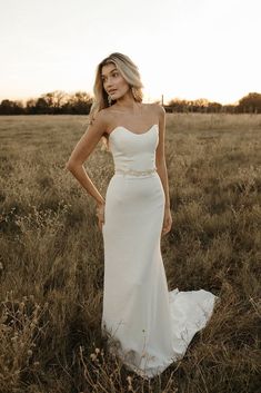 a woman standing in a field wearing a white dress