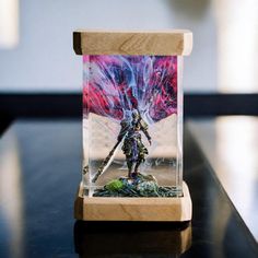 a figurine in a glass case on top of a black table with a red and blue background