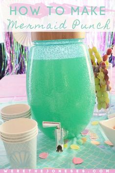 a table topped with cups and bowls filled with green liquid next to a vase full of grapes