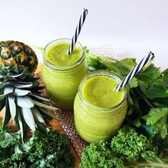 two glasses filled with green smoothie next to broccoli and pineapple