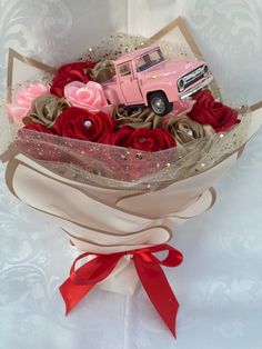 a pink truck is in a bouquet with red roses and ribbon around the edges,