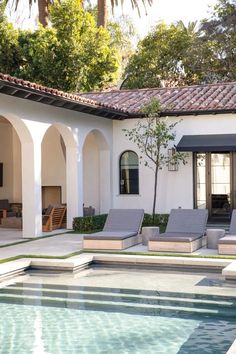 an outdoor swimming pool with lounge chairs next to it