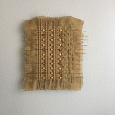 a piece of cloth with buttons on it hanging on the wall next to a white wall