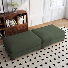 a green ottoman sitting on top of a white rug next to a book shelf filled with books