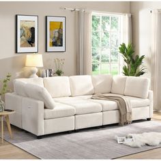 a living room with white furniture and pictures on the wall