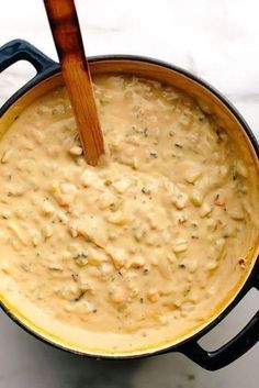 a wooden spoon in a pot filled with food on top of a white countertop