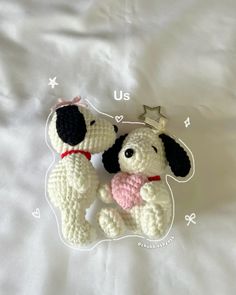 two small crocheted dogs sitting next to each other on top of a bed