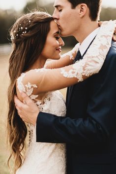 a bride and groom embracing each other in an open field