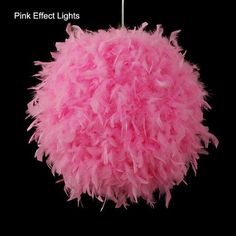 a pink fluffy ball hanging from a black background