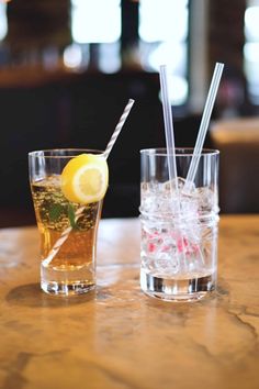 two glasses filled with drinks sitting on top of a table