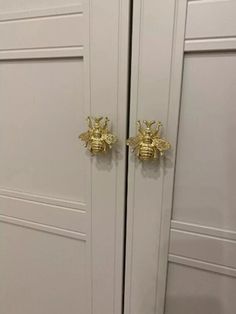 two golden bees are on the handles of white cupboards