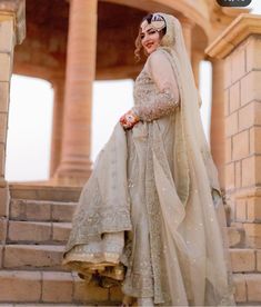 a woman in a wedding dress is standing on some steps with her veil draped over her head