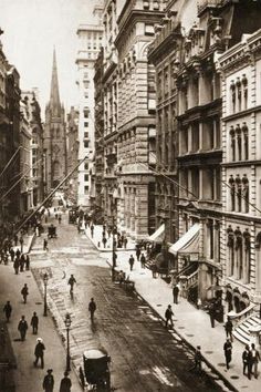 an old black and white photo of people walking down the street in front of tall buildings