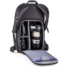 an open backpack with camera equipment in it and a laptop on the bottom compartment,