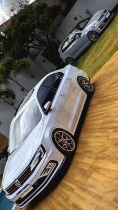 two cars parked next to each other in front of a building with wood flooring