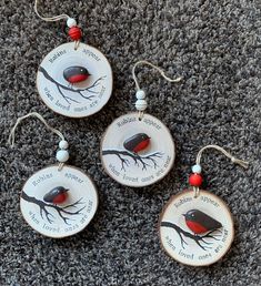 three ornaments with birds on them sitting on the floor in front of a gray carpet