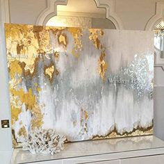 an abstract painting with gold and silver paint on it's walls in a white room