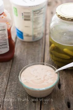 a bowl of pickles sits next to jars of ketchup and mayonnaise