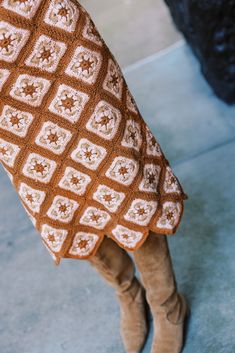 a close up of a woman's legs wearing boots and a crocheted blanket