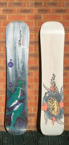 two snowboards sitting next to each other against a brick wall with graffiti on them