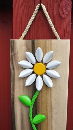 a wooden sign with a flower painted on it's side hanging from a rope