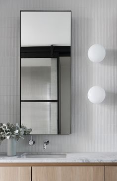 a bathroom with a sink, mirror and vase on the counter top in front of it