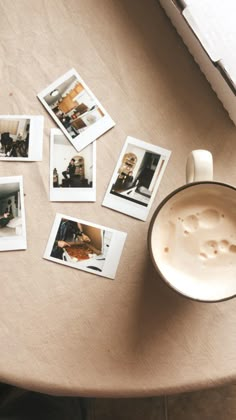 a cup of coffee sitting on top of a table next to some polaroid pictures