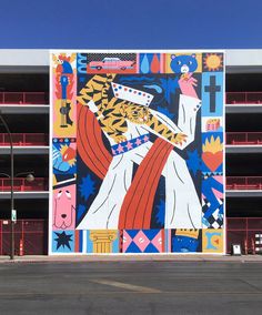 a large mural painted on the side of a building in front of a parking lot