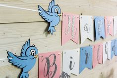 blue and pink paper birds are hanging on the wall