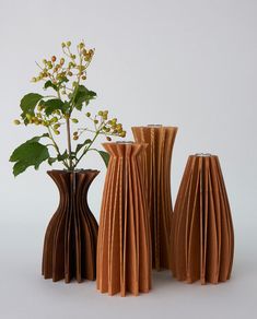 three vases with flowers in them sitting next to each other on a white surface