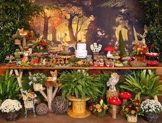 a table topped with lots of potted plants next to a forest scene wallpaper