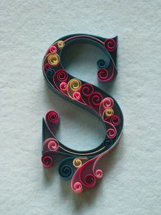 the letter s is made out of paper and has swirly designs on it's sides