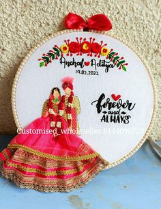 a cross stitch pattern with two dolls in red and gold on a white circle frame