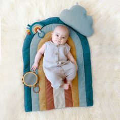 a baby laying on top of a rainbow rug