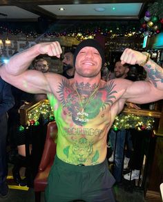 a man with tattoos on his chest and arms is posing in front of a group of people