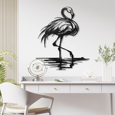 a black and white flamingo standing on top of a desk next to a plant