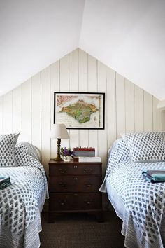 two beds in a room with white walls and wood flooring, one has a blue checkered comforter on it