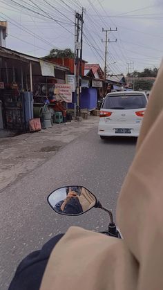 a man riding a motorcycle down a street next to a parked car and a white van