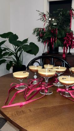 a table topped with wine glasses filled with desserts next to a potted plant