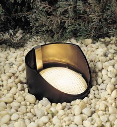 a light that is sitting on some rocks and gravel in front of a planter