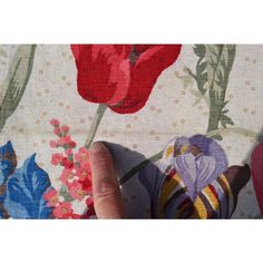 a person's hand is touching the fabric with flowers on it