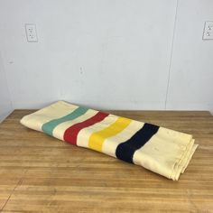 a multicolored striped towel sitting on top of a wooden floor next to a white wall