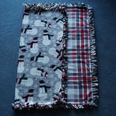 two pieces of fabric with snowmen and plaid on them are laying next to each other