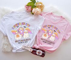 two t - shirts with unicorns on them sitting next to a bottle of booze