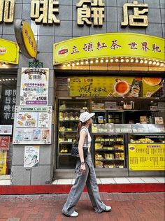 a woman walking down the street in front of a store with chinese writing on it